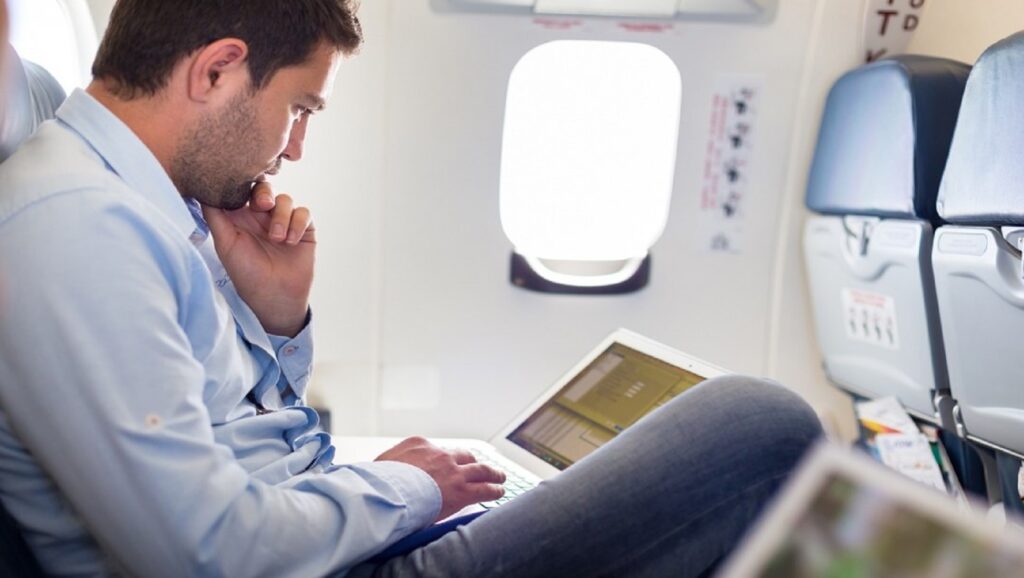 Hombre con ordenador portátil en avión