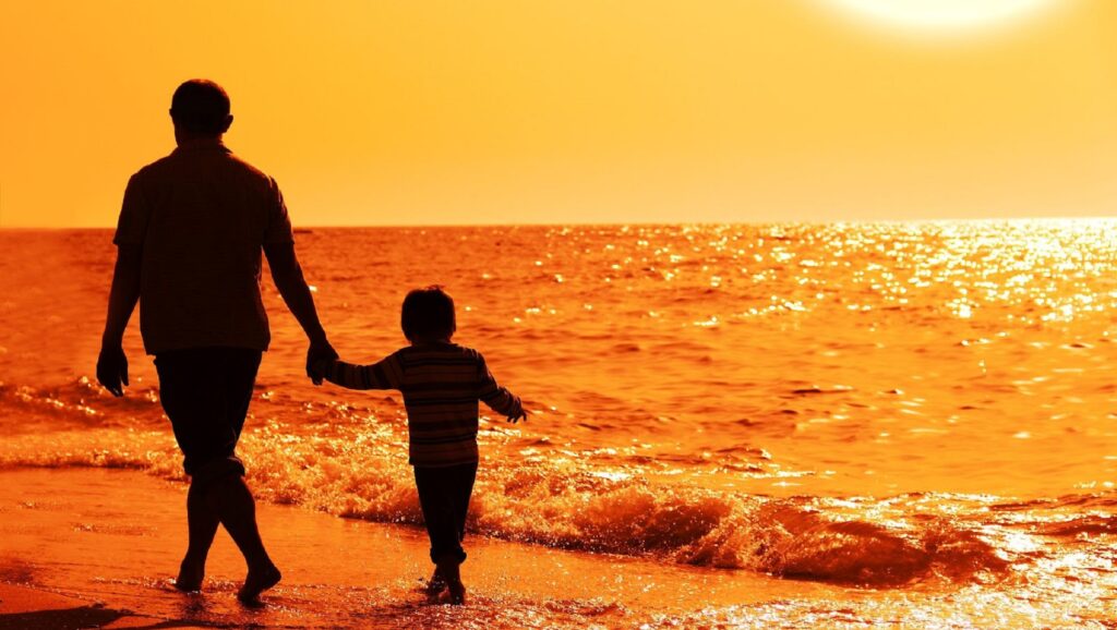 Hombre paseando con niño en la playa