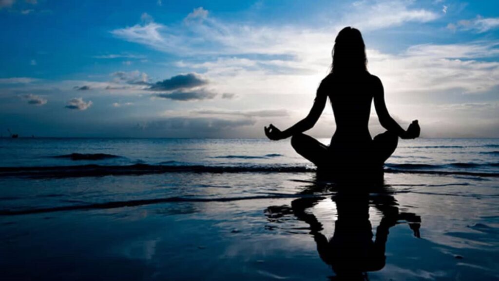 Mujer meditando a la orilla del mar