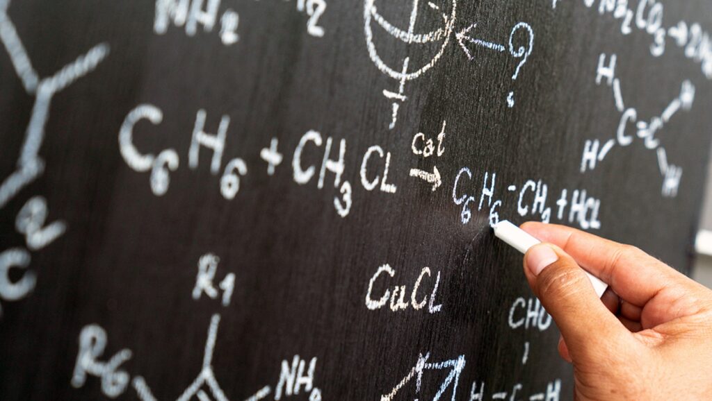 Persona escribiendo fórmulas científicas en una pizarra