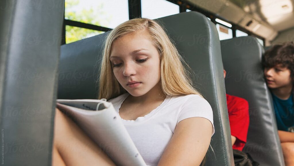 Chica rubia estudiando en el autobús